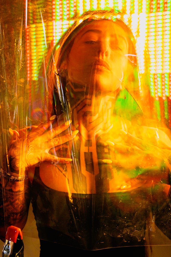 A face seen through textured glass in cool blue light, the surface scattering the portrait into a soft grid of highlights.