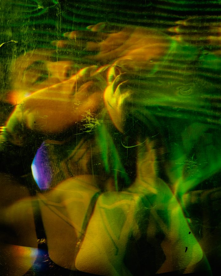 A green-and-red frame, the figure surfacing from a wash of motion blur against a warm textured ground.
