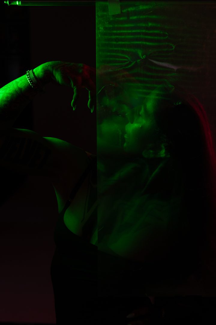 A double-image portrait in green and blue, the figure split and ghosted through textured glass and gel.